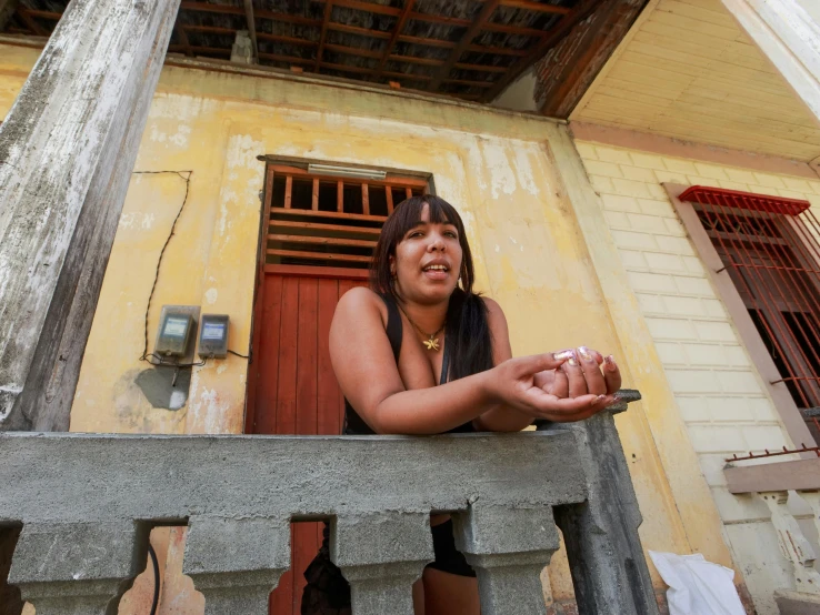 a young woman sits outside her old home with food