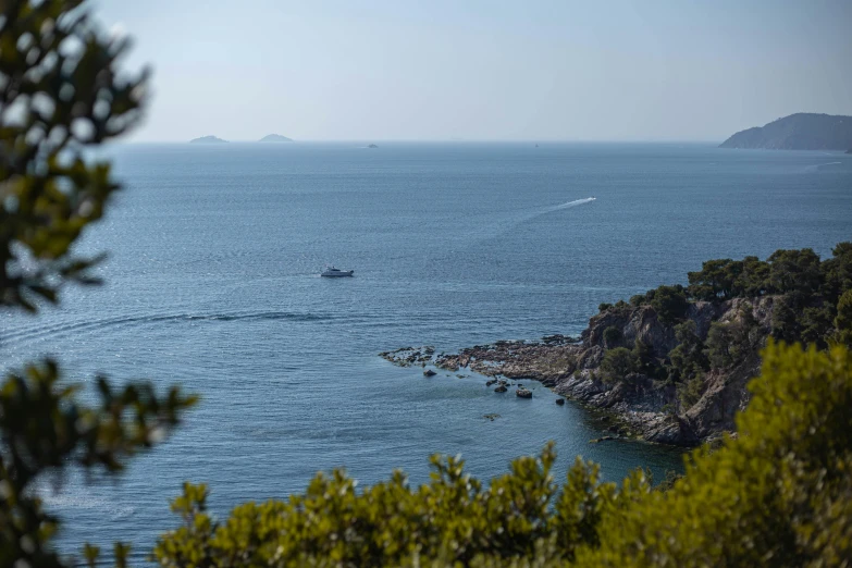 a boat out on the ocean with green vegetation on shore