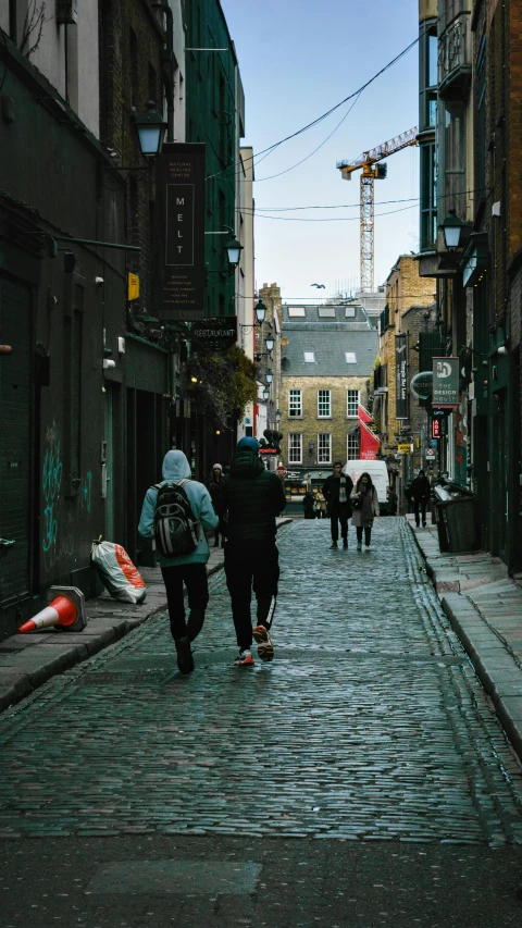 people walking on a cobblestone street in a downtown area