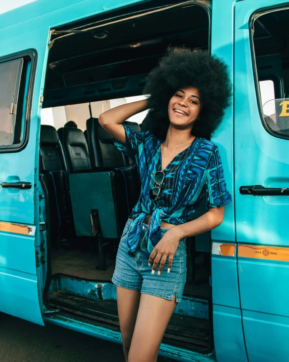 a woman standing by the open door of a bus with her hair in the air