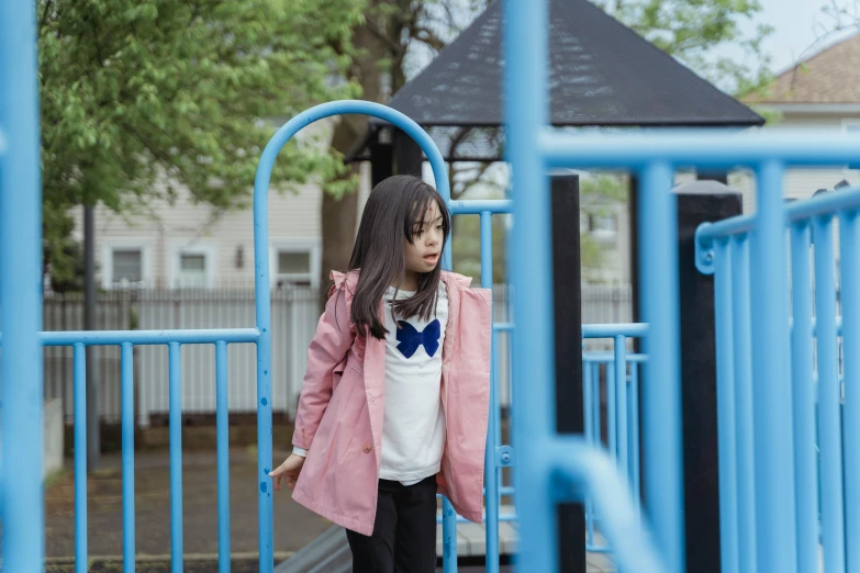 a little girl stands on a blue structure