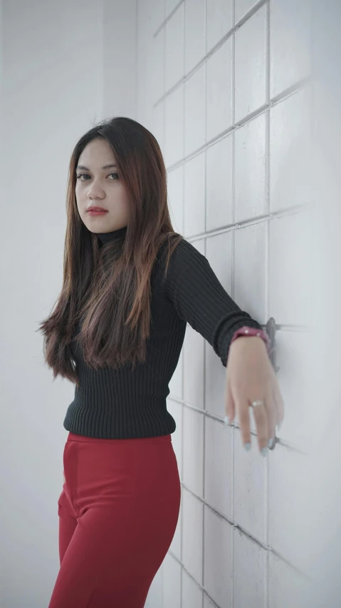 a woman leans against a wall with one hand