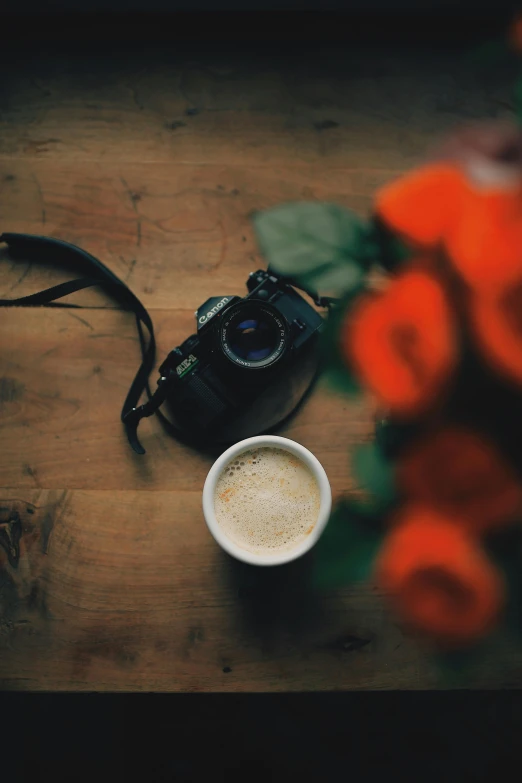 a camera sitting on top of a table next to a cup of coffee