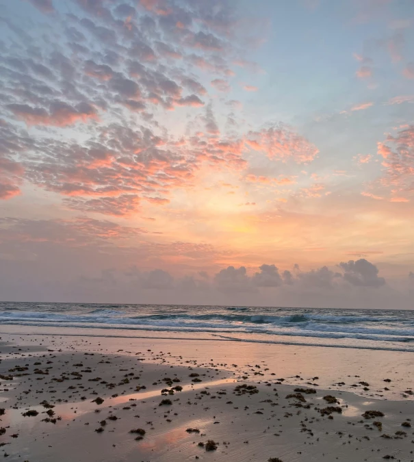 the sunset over the ocean with waves coming in