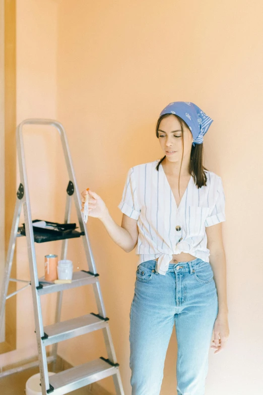 a young woman stands in front of a step ladder and smiles