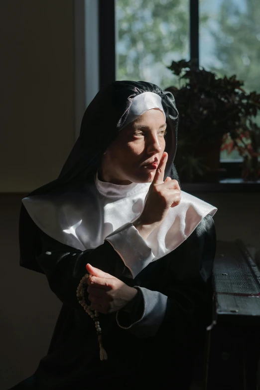 a nun poses for the camera near a window