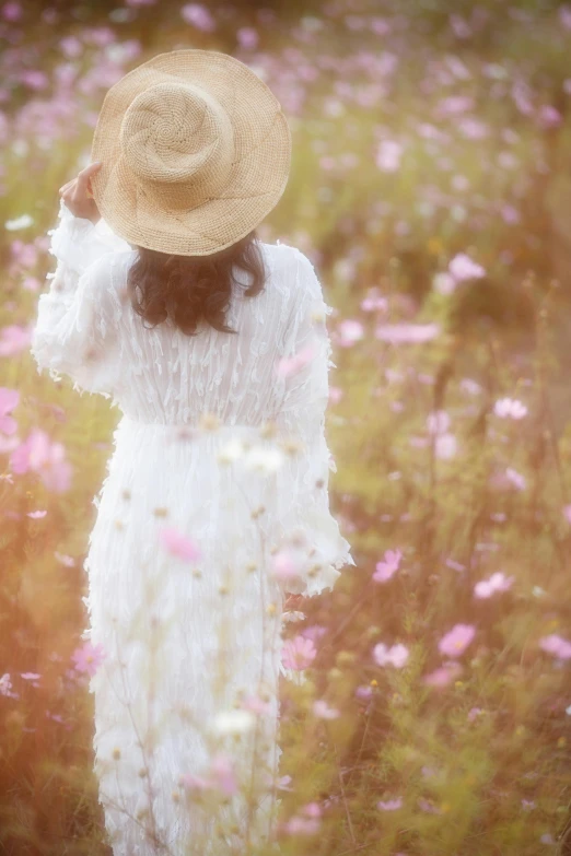 a woman wearing a hat in the field with flowers