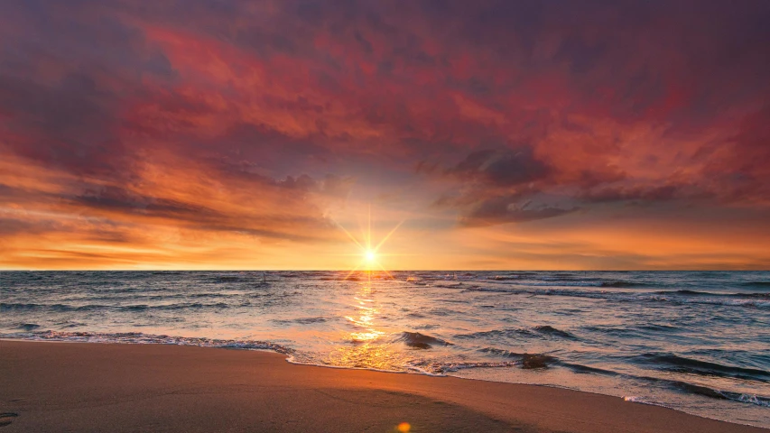 a sunset over the ocean and a wave coming in from the water