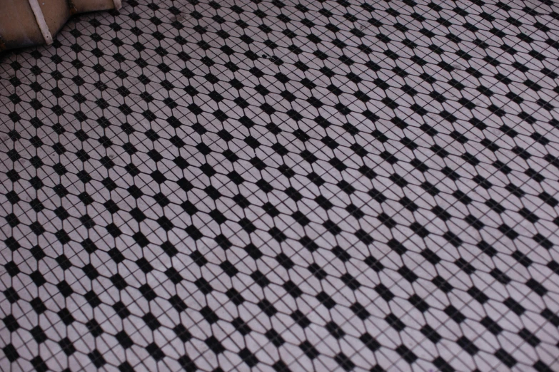 an interesting white and black tiled floor with the reflection of a teddy bear