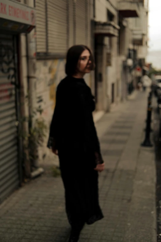 a woman is standing on the sidewalk with an umbrella