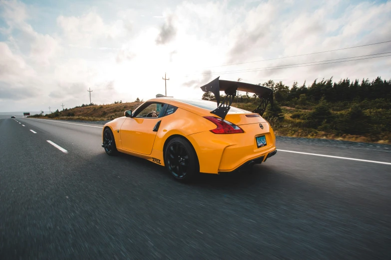 yellow sports car driving down the road with a surf board on the back end