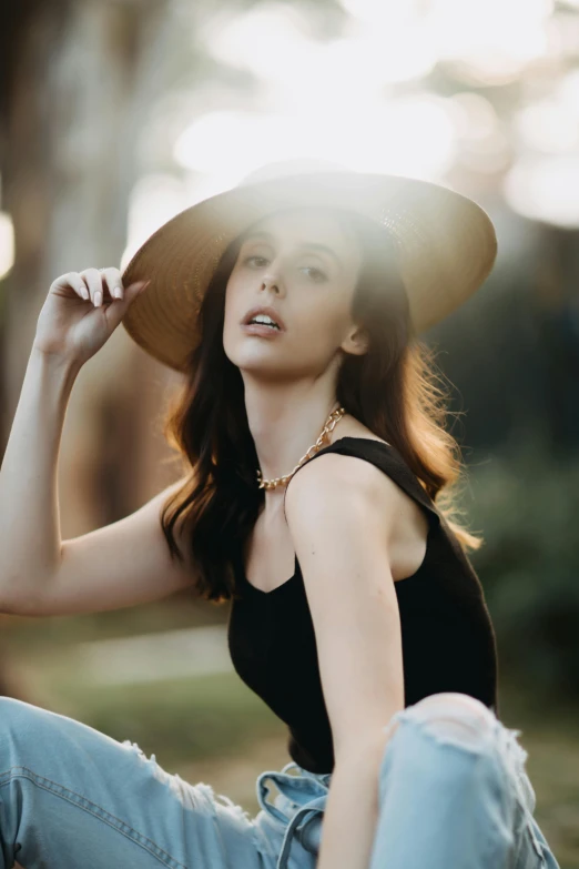 a young woman wearing a hat while sitting on a tree