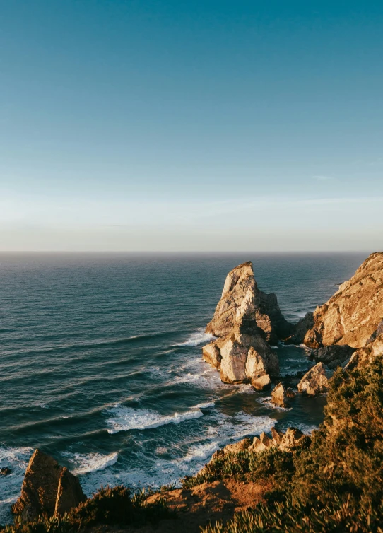 a rocky coast surrounded by waves under a blue sky