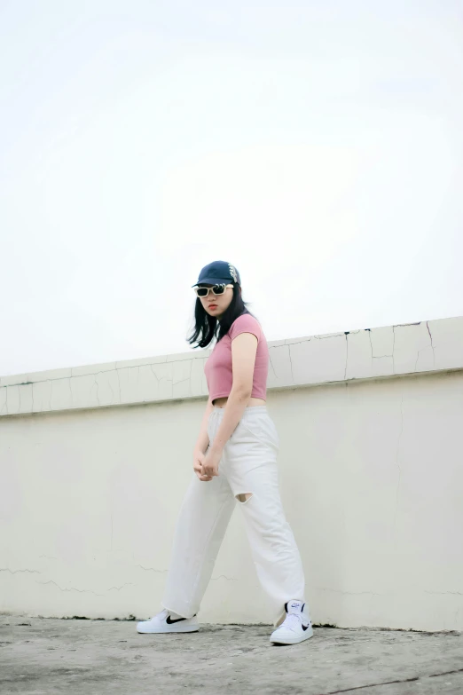 a young woman poses for the camera near a cement wall