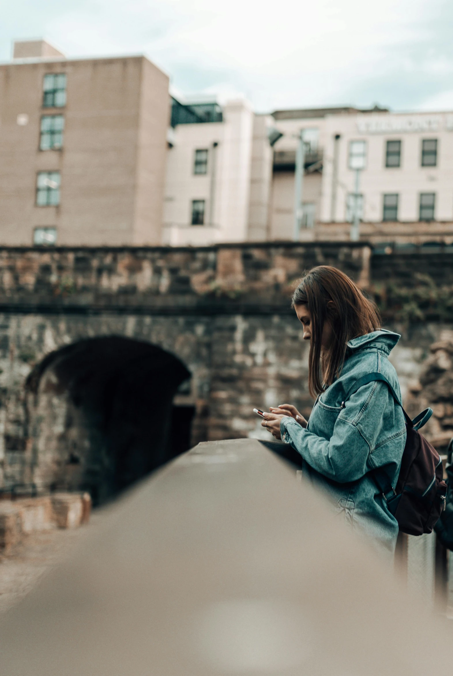 a person looking at their cell phone while standing by some bridges