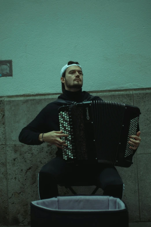 man sitting outside with an accordion on the floor