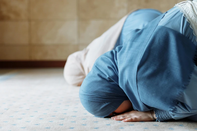 a woman in a blue top doing a hand stand on a bed