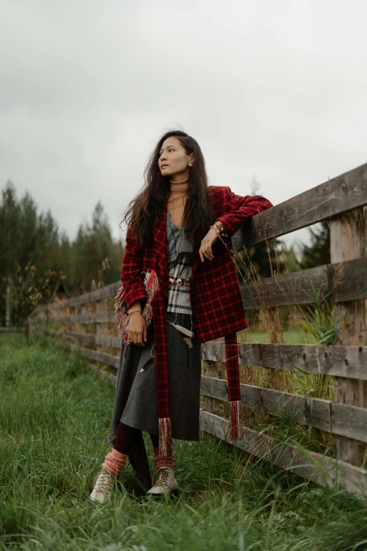 a woman standing in the grass near a fence