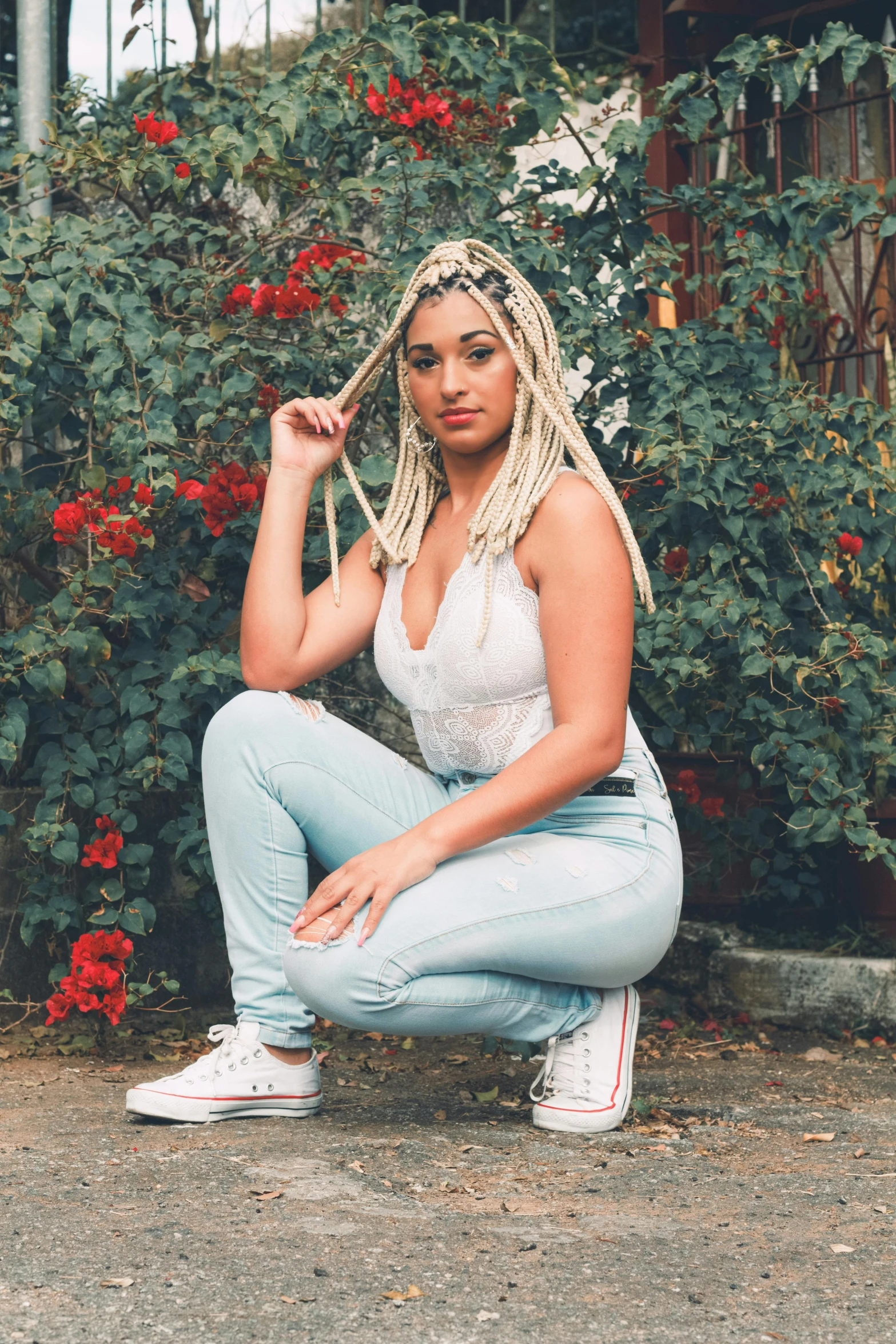 the young woman is posing outside by some flowers