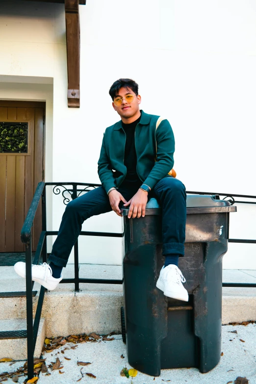 a man with an all green shirt is sitting on a trashcan