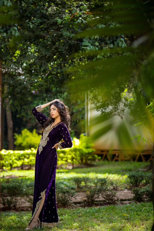 a beautiful woman in an indian dress is standing under a tree