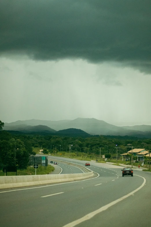 a long road going up a hill under a cloudy sky