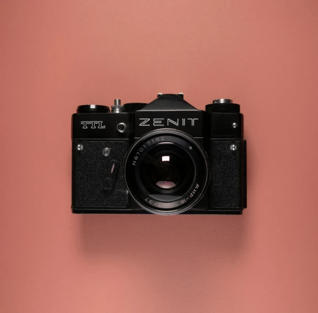 an old fashioned camera on a pink wall