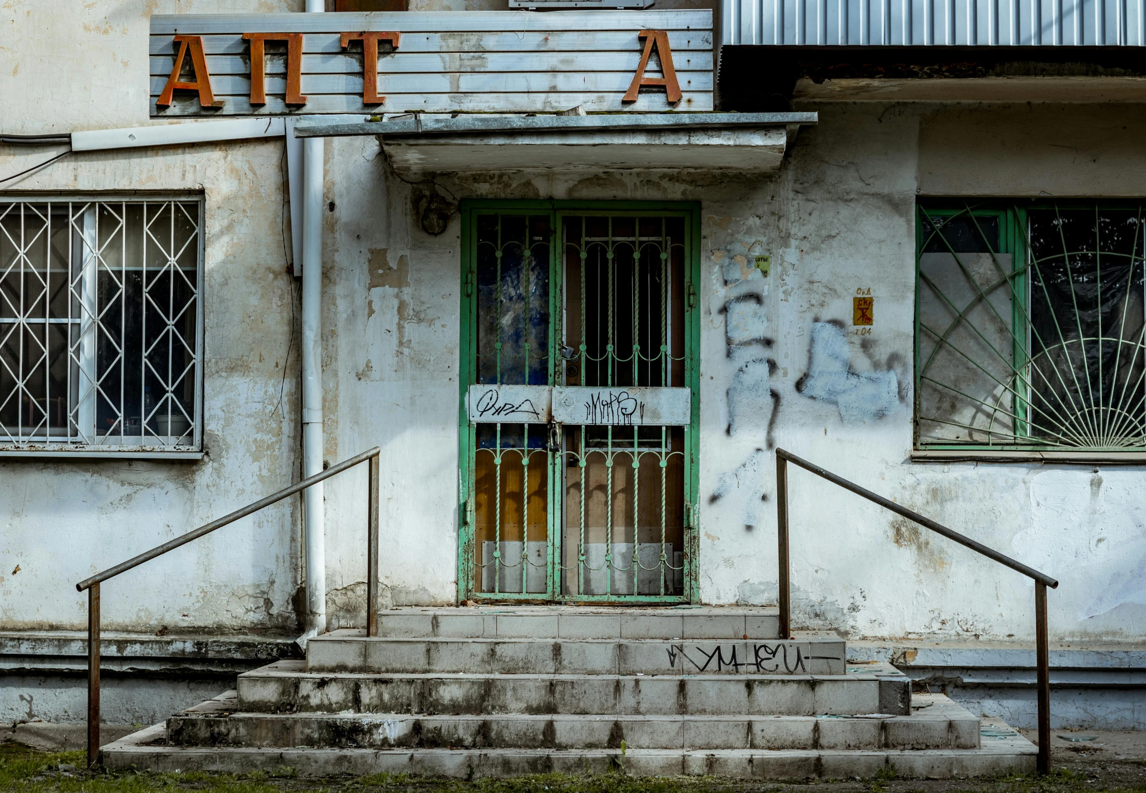 a run down building with a green door and some metal steps