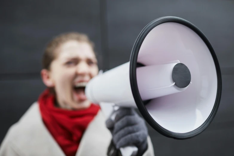 a man with scarf and jacket shouting into a bullhorn