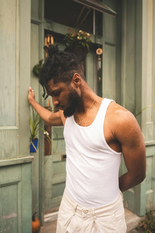 a man wearing white tank top and white shorts standing outside of a building