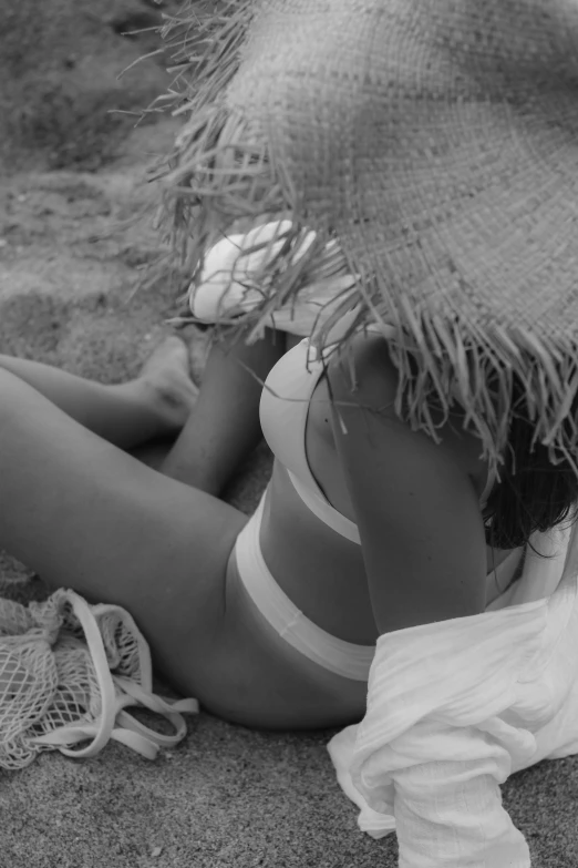 a woman is laying in the sand wearing a hat