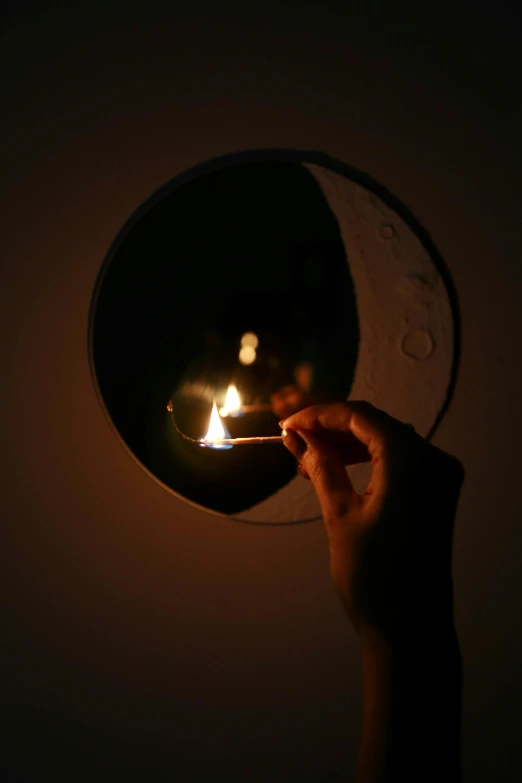 someone holding up their small fire in the dark