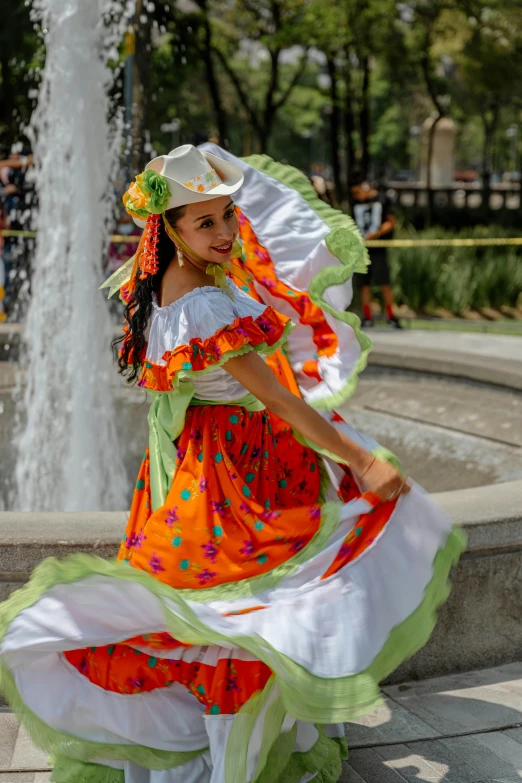 a woman is dressed up and dancing near a fountain