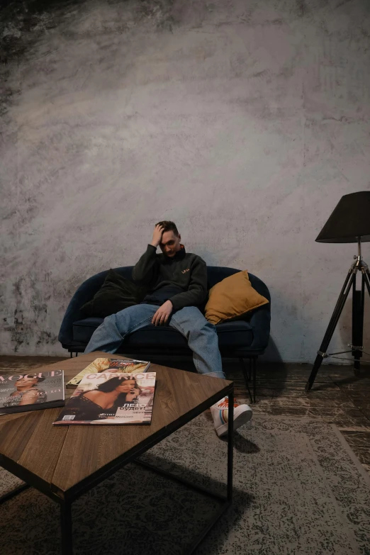 a man is relaxing on a couch near a wooden table