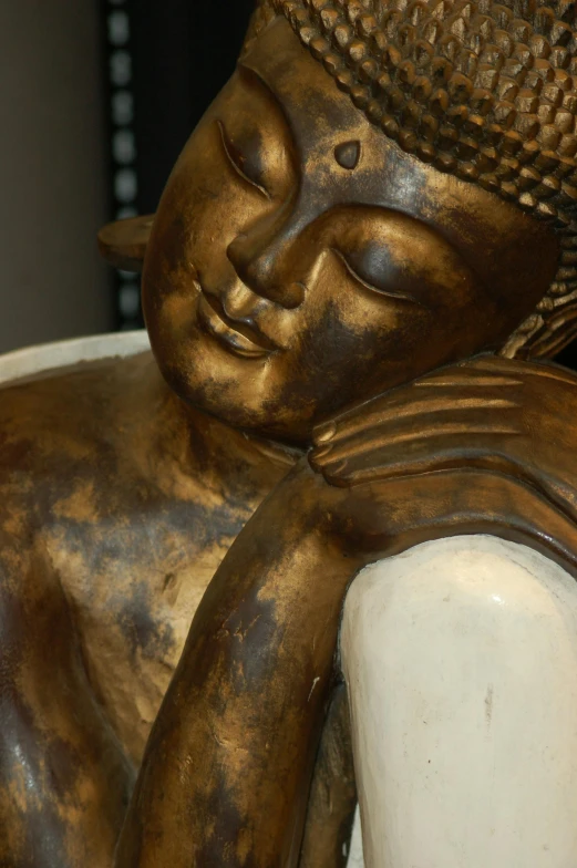 a close up of a bronze buddha statue with a hat on it