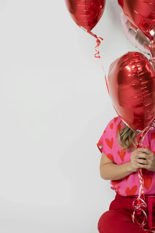 a little girl holding two red balloons