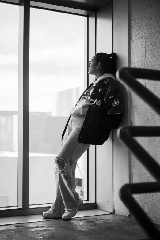 a person stands in front of a window with his hand on the back of his head