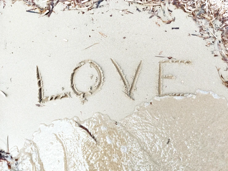 the word love drawn in sand with an umbrella in the background