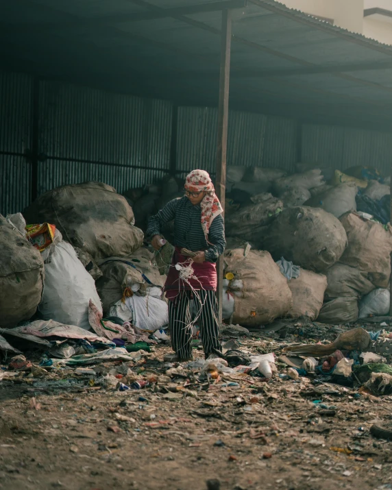 woman with a sack in hand standing in garbage