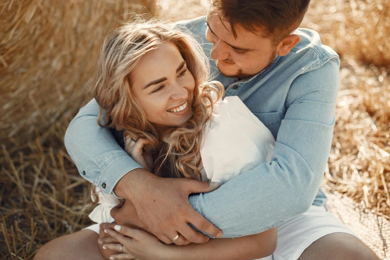 a couple emcing each other in front of a hayfield