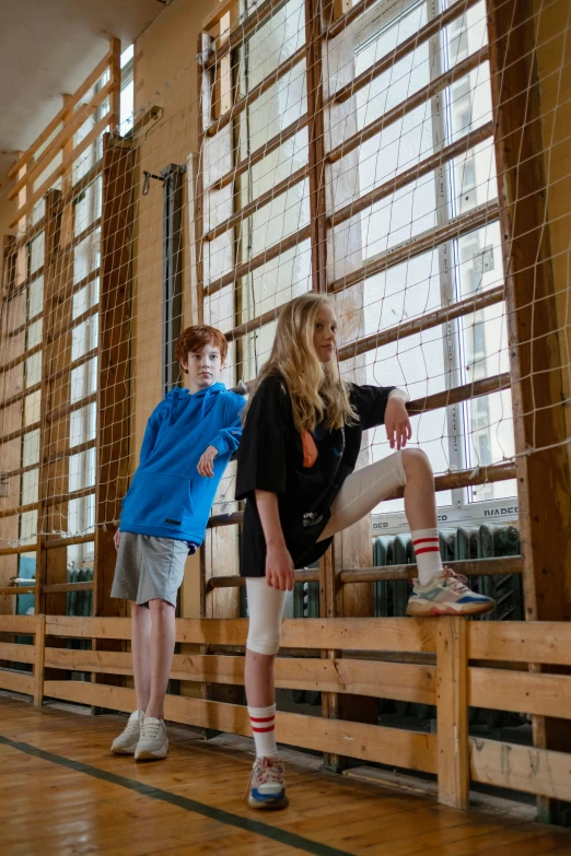 two boys wearing socks standing up on some wooden slats