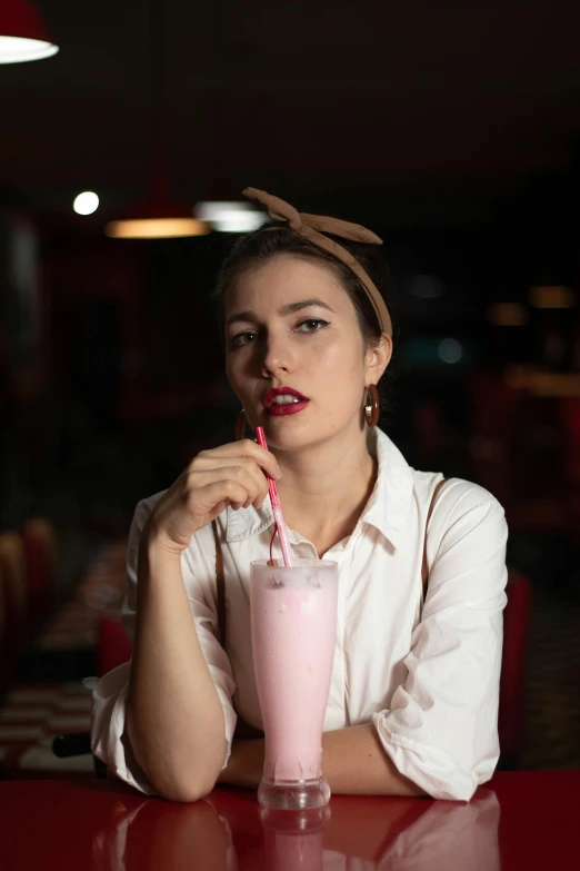 a woman sitting at a red table with a drink