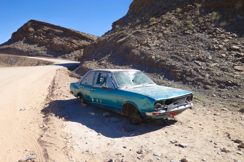 an old car is parked in the dirt