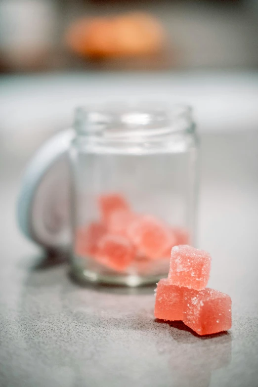 several small gummy bears on the counter in front of a jar