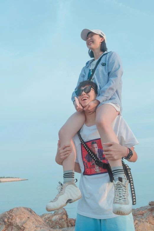 young couple standing atop man on top of woman at beach