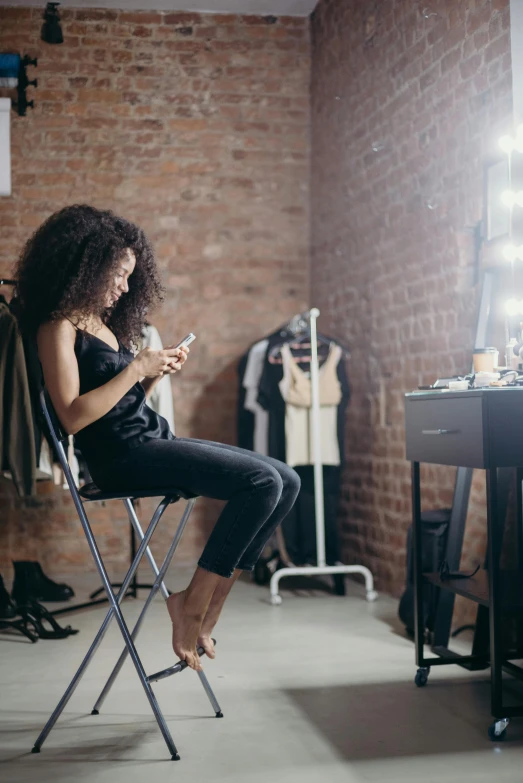 a woman sitting in a chair looking at her cell phone