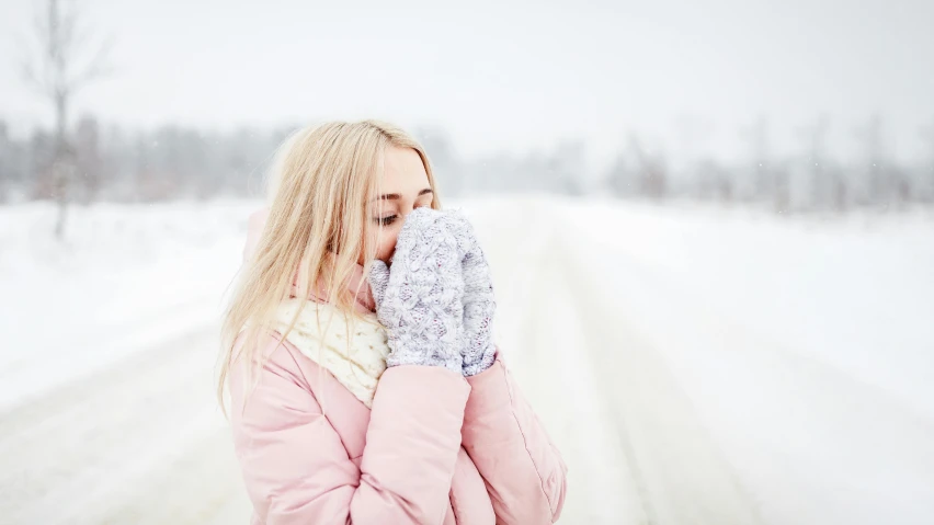 a woman standing in the snow holding her mitts