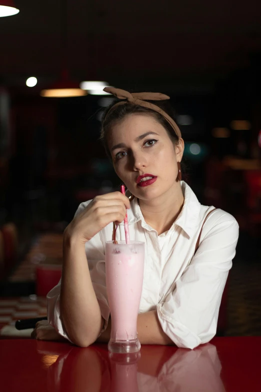 a girl is drinking a pink drink at the table