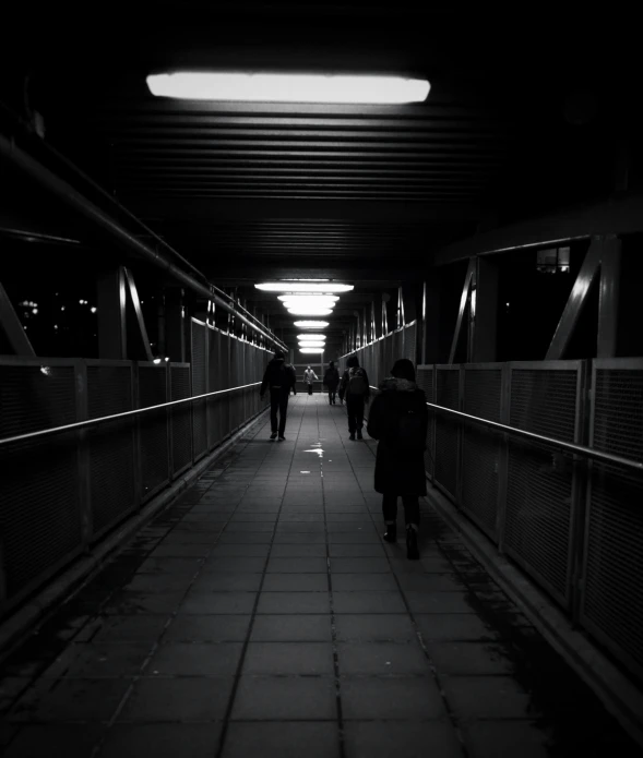 people walk down an empty walkway in a dark city