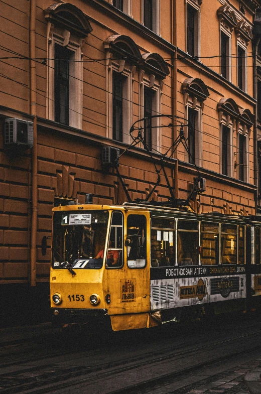 a yellow train traveling past a building next to a street